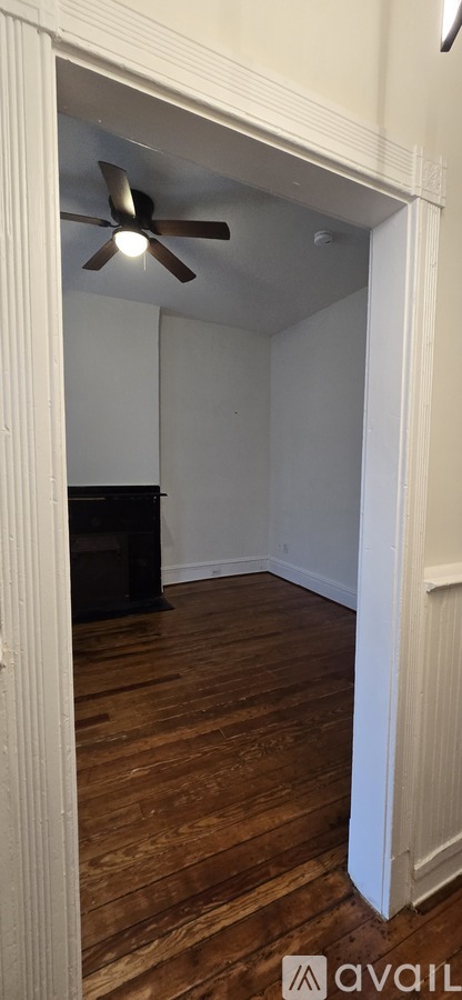A room with a ceiling fan and wooden flooring.