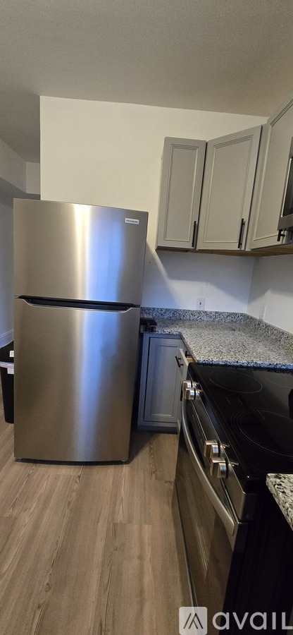 A kitchen with a stainless steel refrigerator and black countertop.