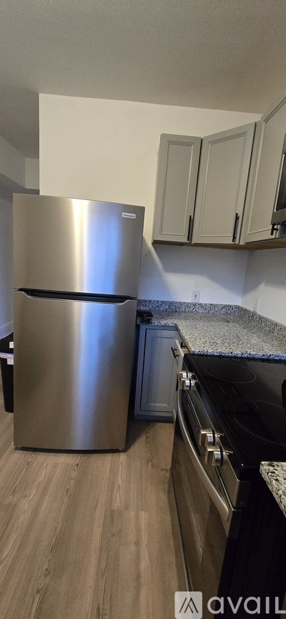 A kitchen with a stainless steel refrigerator and black countertop.
