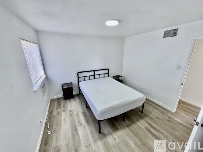 A bedroom with a bed, nightstand, and window.