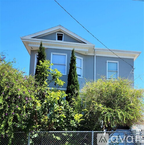 A grey house with trees in front.
