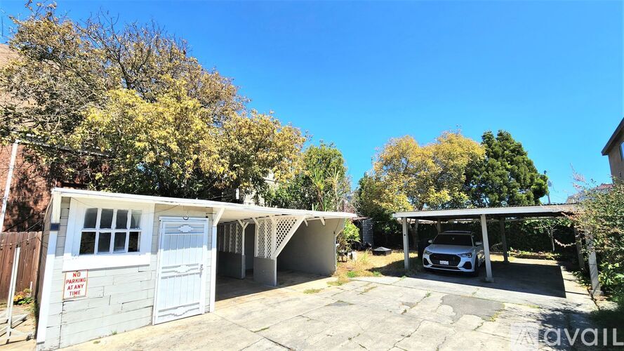 A car is parked in a driveway under a covered area.