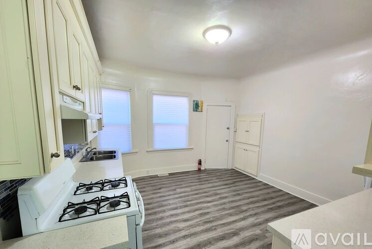 A kitchen with a white stove top oven and a window with blinds.