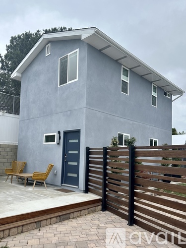 A grey house with a black door and a wooden fence.