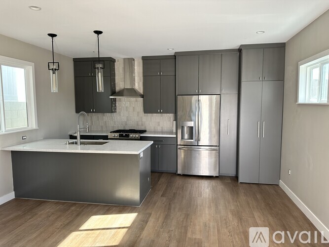 A modern kitchen with stainless steel appliances and wooden flooring.
