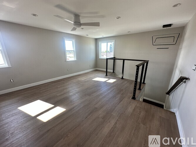 A spacious room with wooden flooring and a ceiling fan.