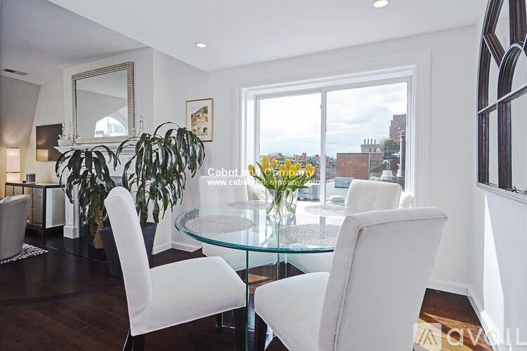 A modern dining room with a glass table and white chairs.