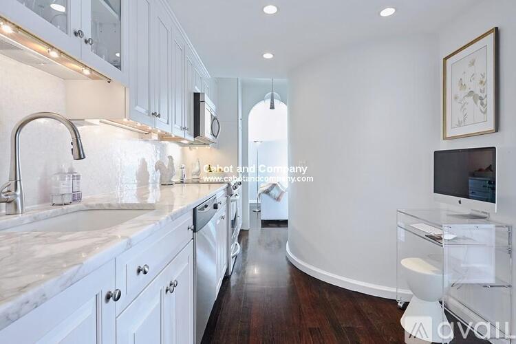 A modern kitchen with white cabinets and a marble countertop.
