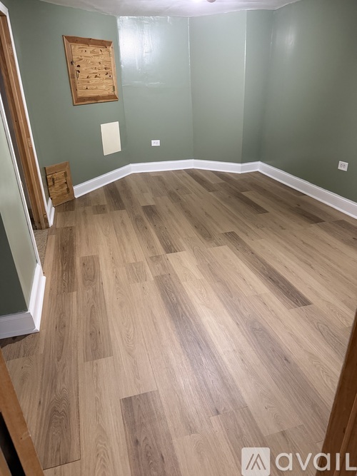 A room with wooden flooring and a green wall.