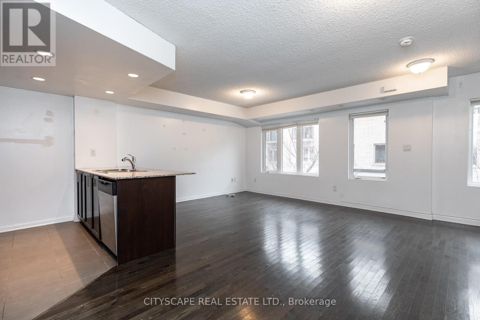 A spacious room with wood flooring and a kitchen island.