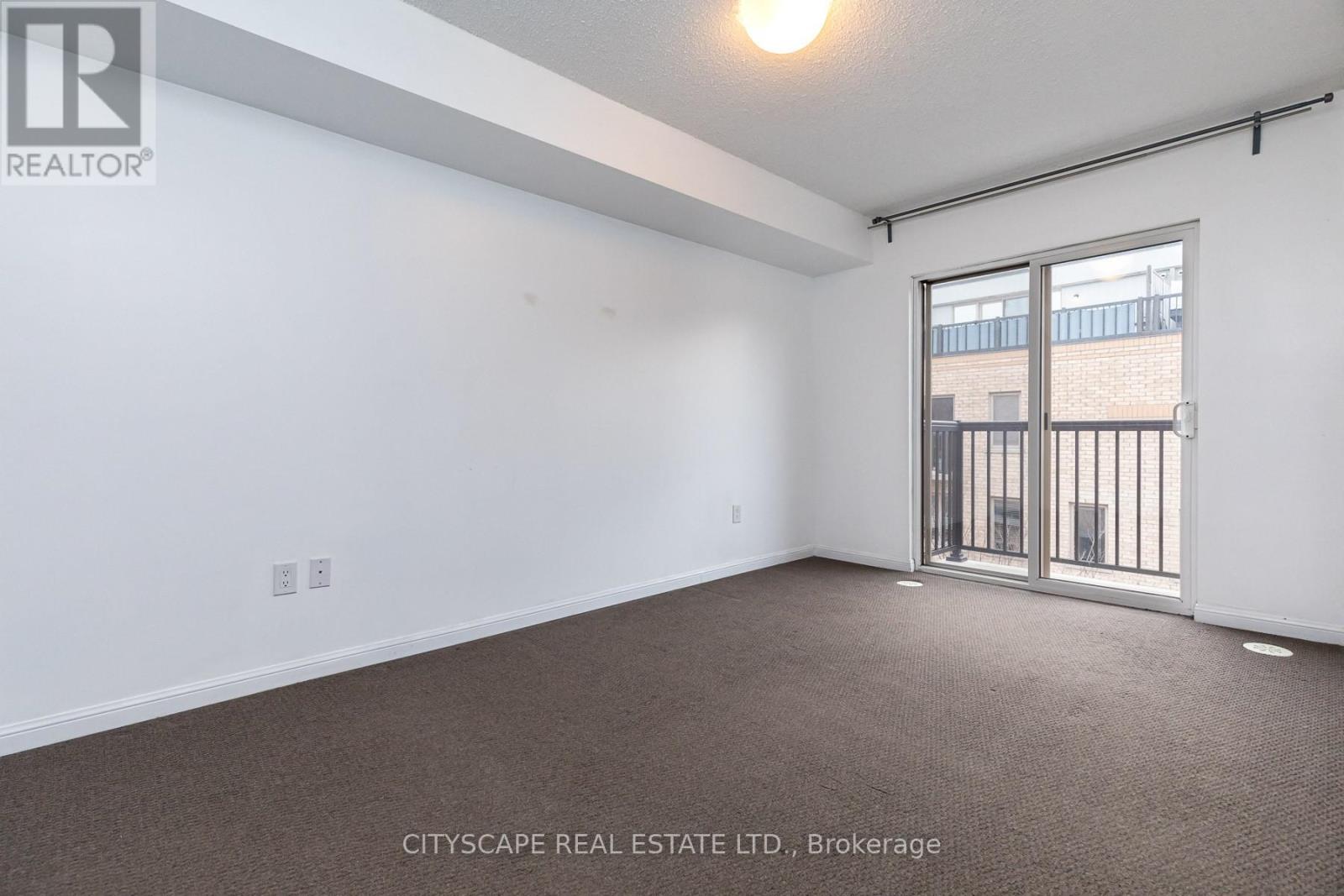 A large, empty room with a carpeted floor and a window with a view of a building outside.