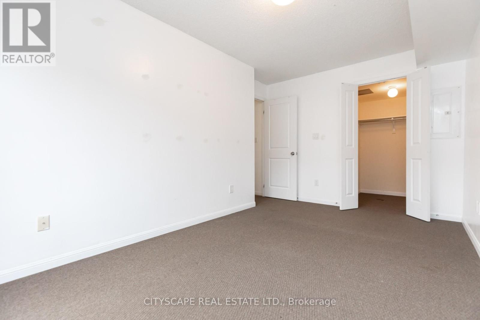 A spacious room with white walls and carpeted floor.