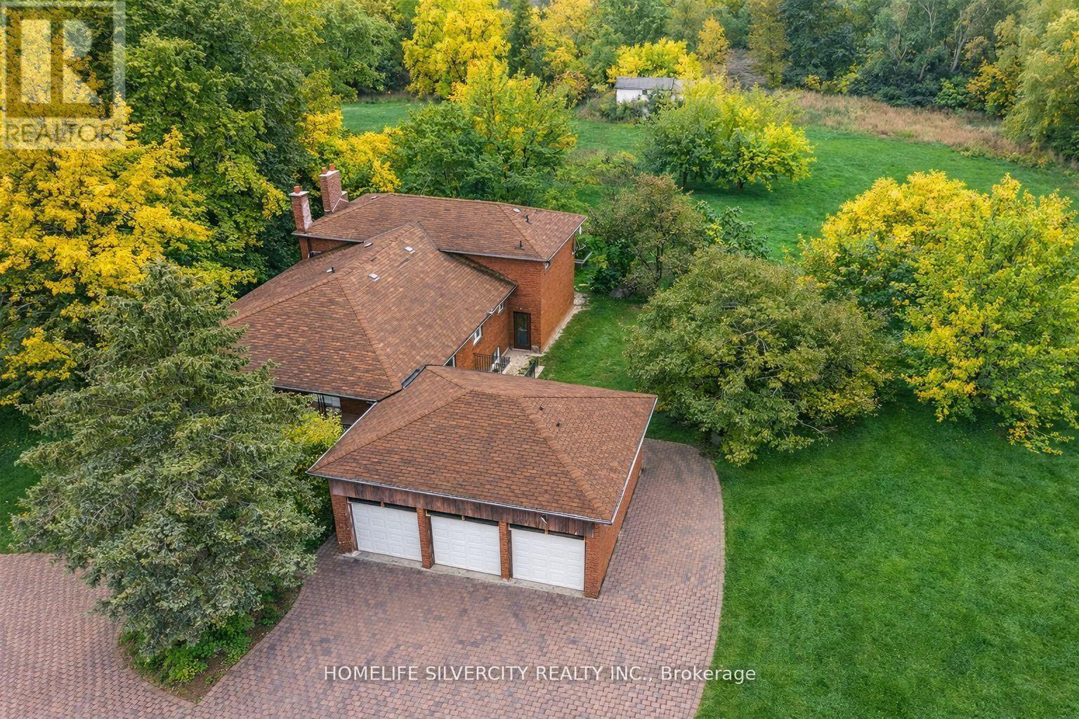 A house with a brown roof and a garage is surrounded by trees.