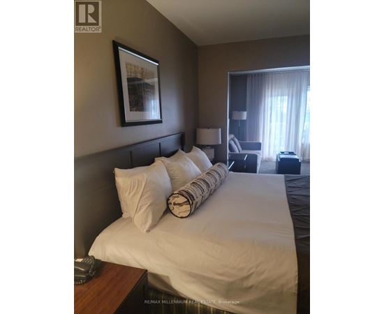 A bedroom with a large bed and a picture frame on the wall.