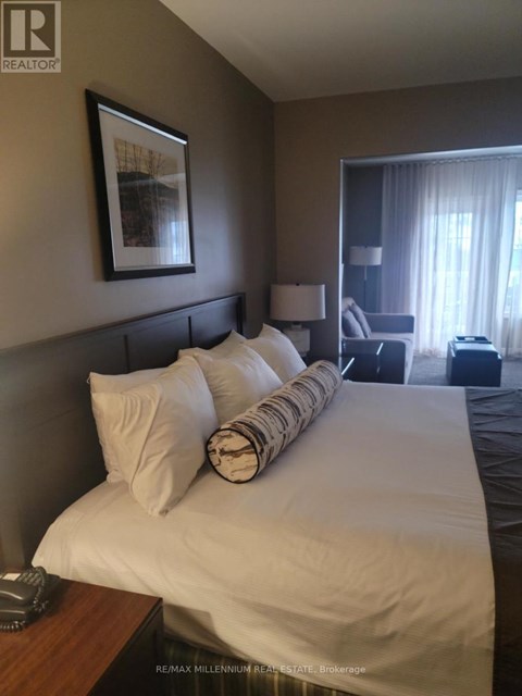 A bedroom with a large bed and a picture frame on the wall.
