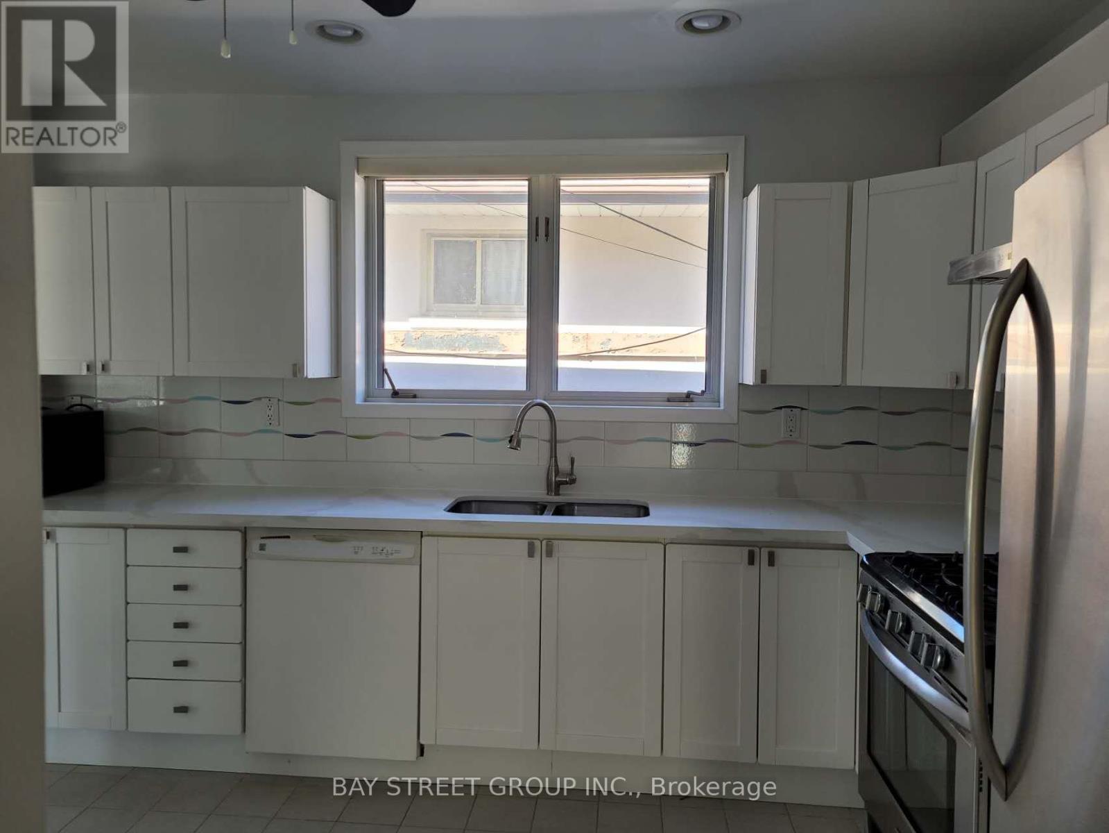 A kitchen with white cabinets and a window overlooking the street.