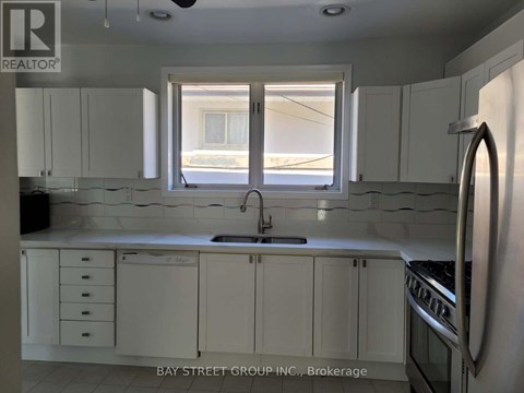 A kitchen with white cabinets and a window overlooking the street.
