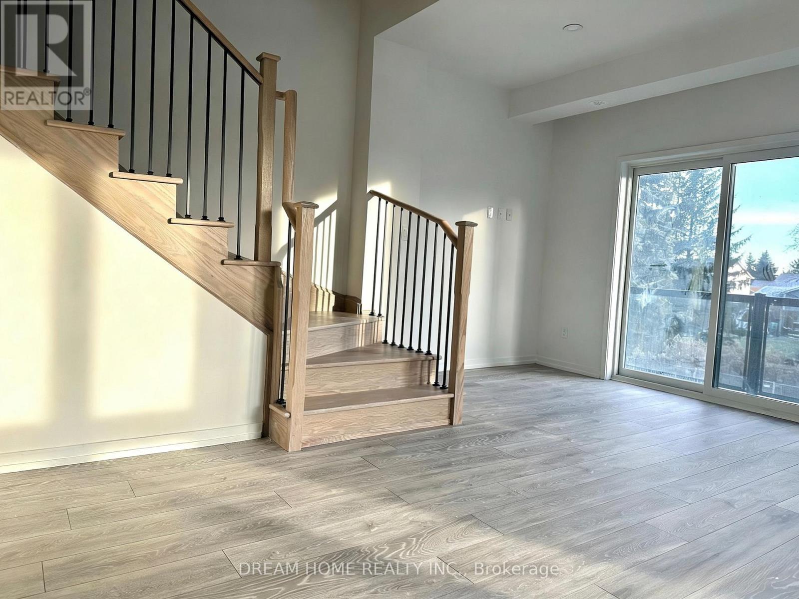 A spacious room with a staircase and a view of a snowy landscape outside the window.