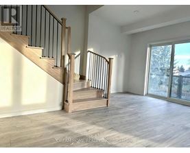A spacious room with a staircase and a view of a snowy landscape outside the window.