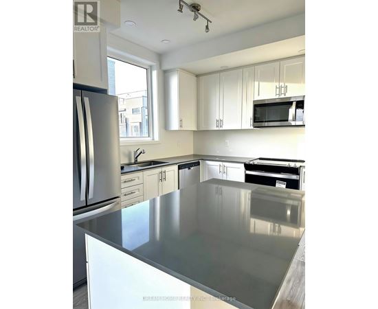 A kitchen with a stainless steel counter top and white cabinets.