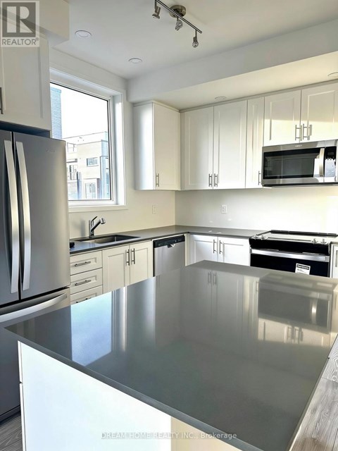 A kitchen with a stainless steel counter top and white cabinets.