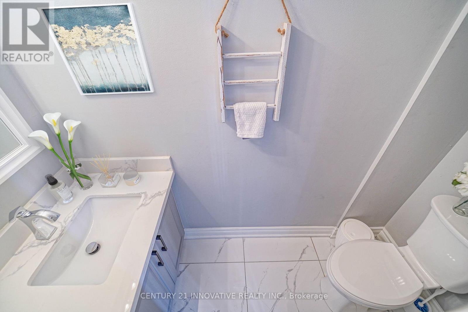 A white toilet is in a small bathroom with a white sink.