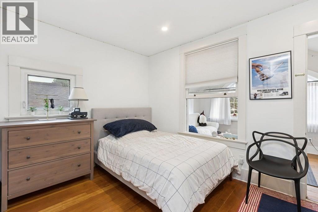 A bedroom with a bed, a chair, and a dresser.