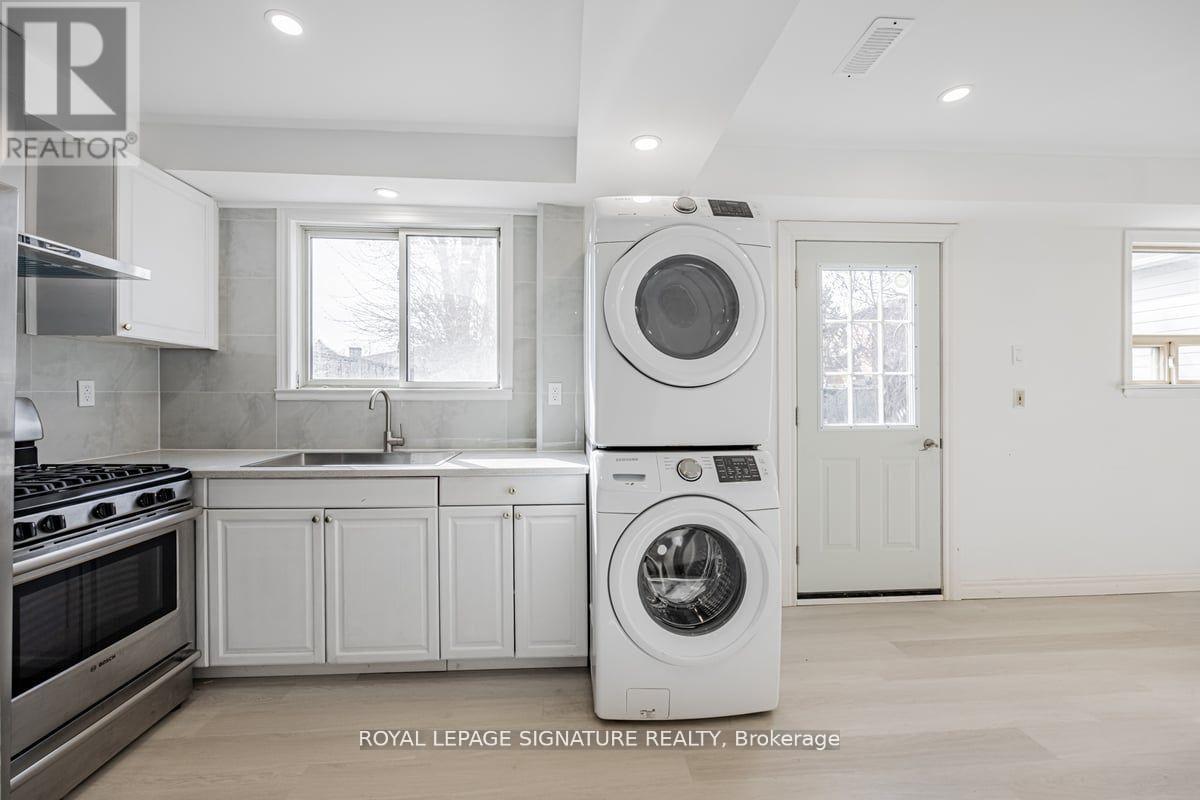 A white washing machine is in a kitchen with white cabinets.