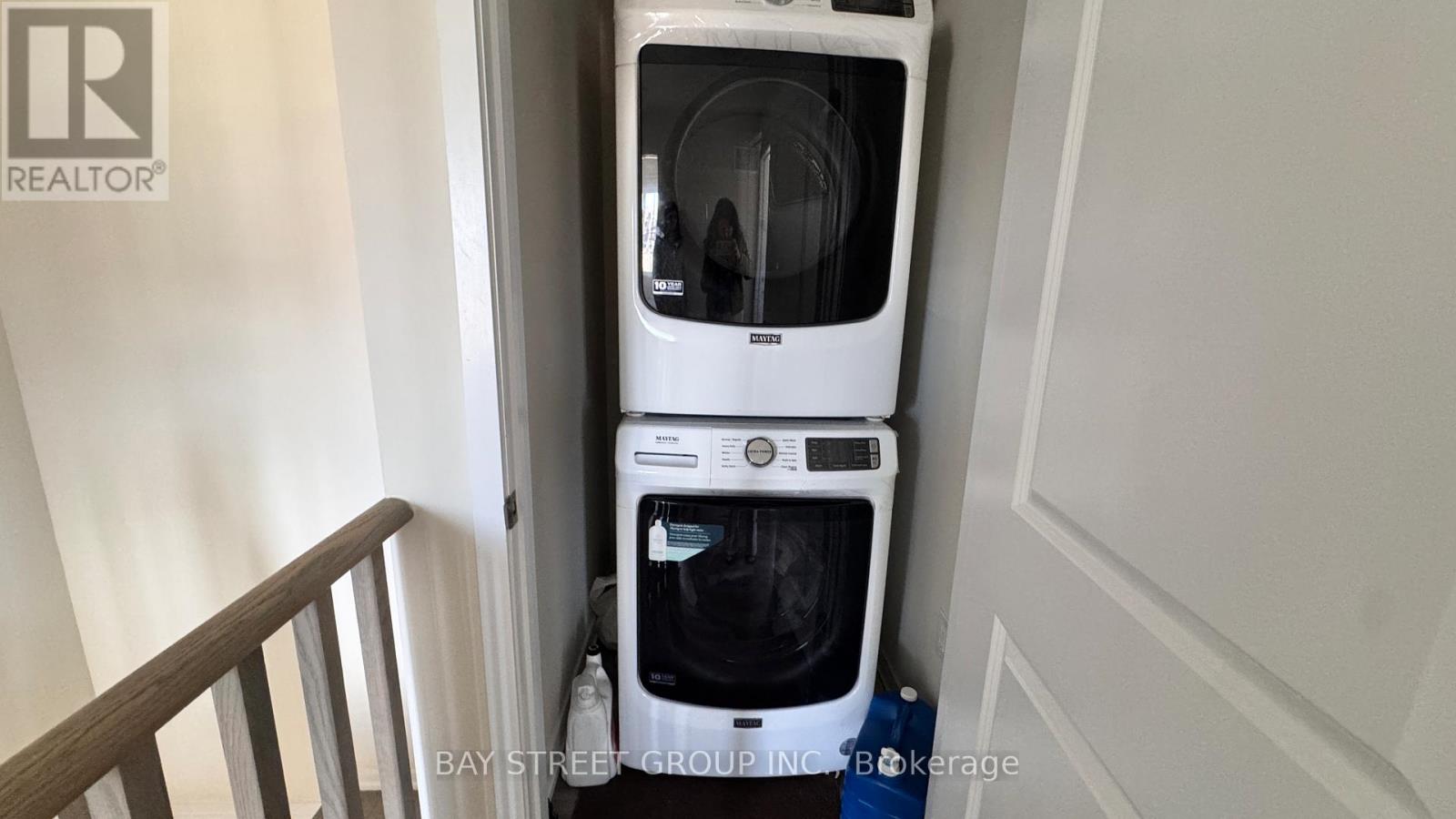 A white dishwasher and washing machine are stacked on top of each other in a small space.