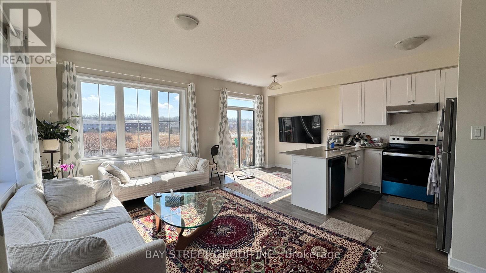 A well-lit living room with a kitchen in the background.