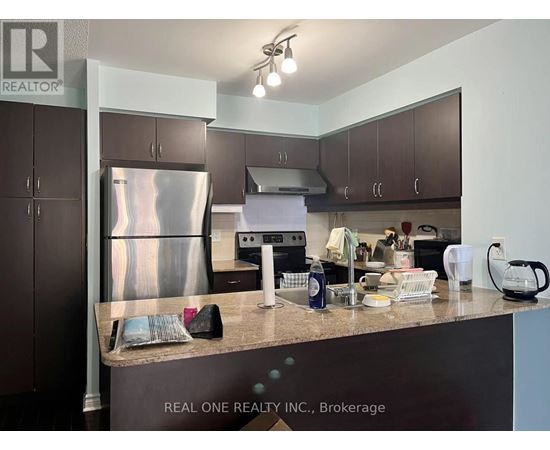 A kitchen with a stainless steel refrigerator and a countertop with various items on it.