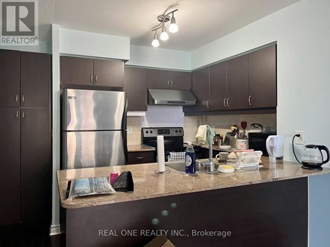 A kitchen with a stainless steel refrigerator and a countertop with various items on it.
