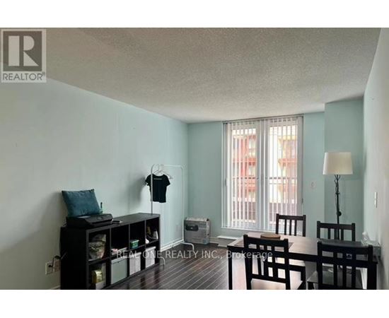 A room with a table and chairs, a bookshelf, and a window with curtains.