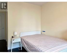 A bedroom with a bed, nightstand and lamp.