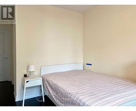 A bedroom with a bed, nightstand and lamp.