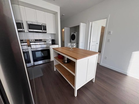 A kitchen with a wooden island and stainless steel appliances.