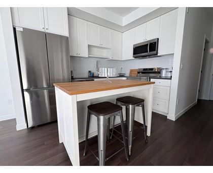 A kitchen with white cabinets and a wooden island.