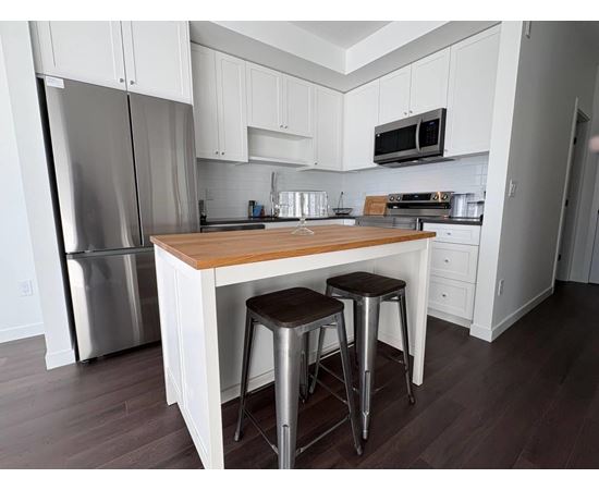 A kitchen with white cabinets and a wooden island.