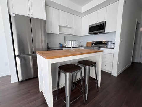 A kitchen with white cabinets and a wooden island.