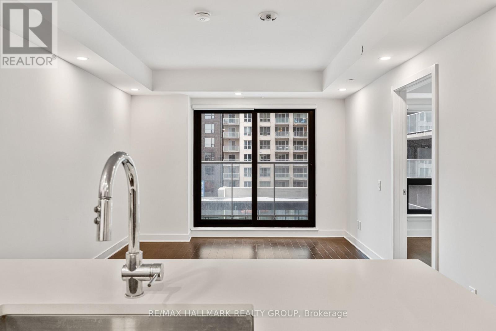 A spacious room with wooden flooring and a large window showing a cityscape.
