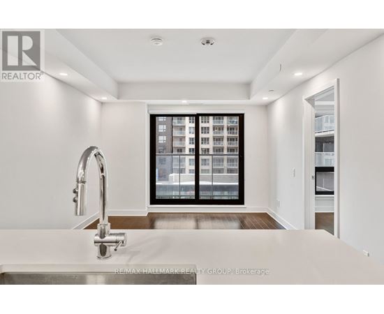 A spacious room with wooden flooring and a large window showing a cityscape.