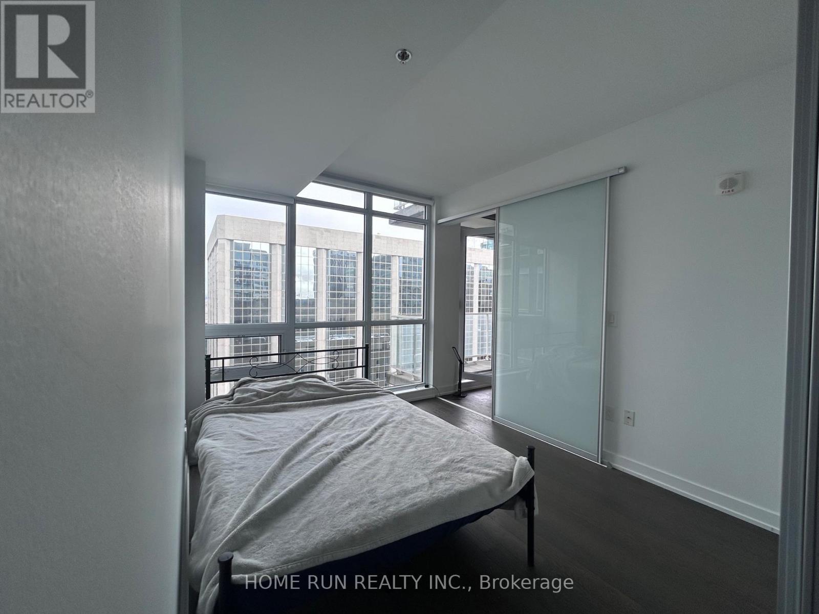 A bedroom with a bed and a window overlooking a cityscape.
