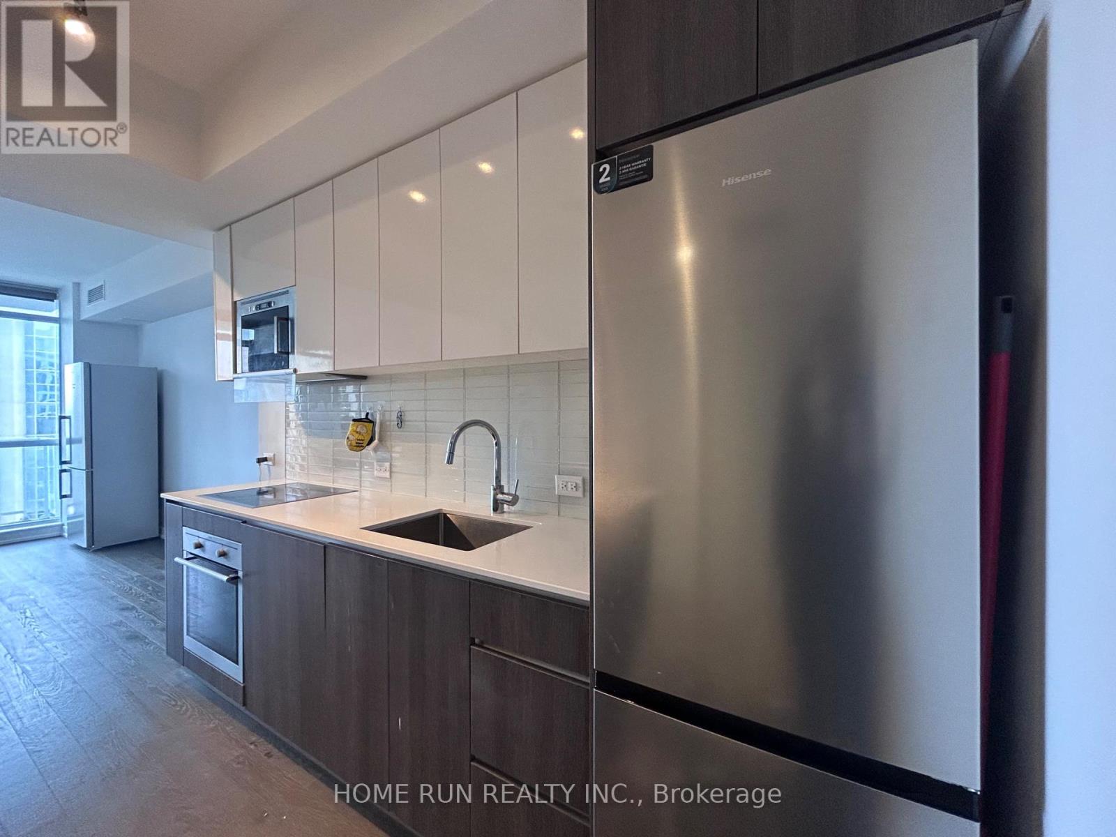 A modern kitchen with a stainless steel refrigerator and wooden cabinets.