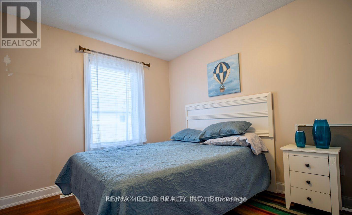 A bedroom with a bed, nightstand, and window.
