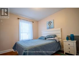 A bedroom with a bed, nightstand, and window.