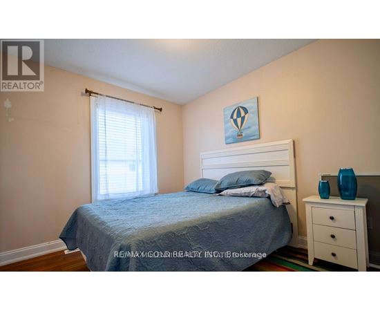 A bedroom with a bed, nightstand, and window.