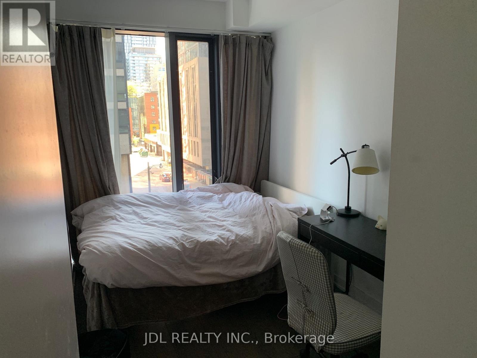 A bedroom with a bed, desk, and chair.