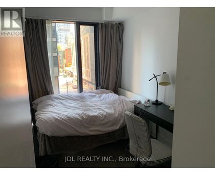 A bedroom with a bed, desk, and chair.