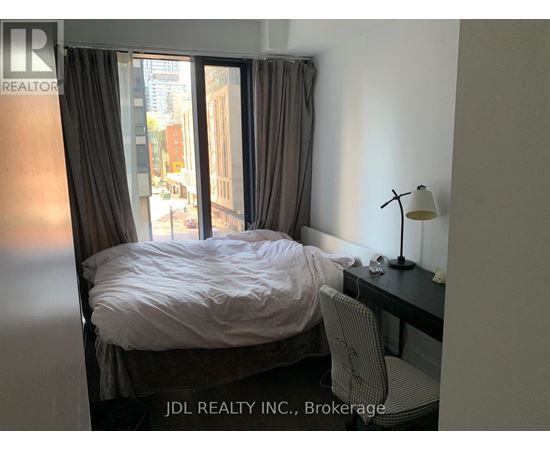 A bedroom with a bed, desk, and chair.