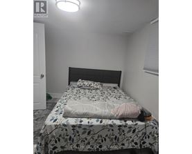 A bedroom with a bed covered in a leaf patterned sheet.